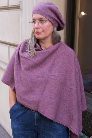 Das Cape ist schräg getragen und mit dem Beret in derselben Farbe kombiniert.